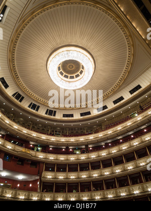 Decke und Balkone der Haupthalle an der Wiener Staatsoper. Ein großer Kronleuchter dominiert den kreisförmigen Raum. Stockfoto