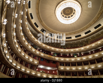 Decke und Balkone der Haupthalle an der Wiener Staatsoper. Ein großer Kronleuchter dominiert den kreisförmigen Raum. Stockfoto