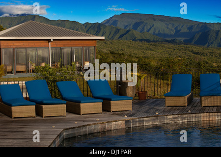 Hotel-Pool und Außenbereich Diana Dea Lodge. Befindet sich 600m, mit Blick auf das Dorf Sainte Anne, Diana Dea schlanke, moderne Ästhetik und die atemberaubende Landschaft es auseinander als Ort etwas Besonderes. Umgeben von endlosen Weiten des üppigen grünen Land, spürt in Richtung Diana Dea wärst du weit weg von zu Hause... in der bestmöglichen Weise. Mit einer kleinen Auswahl von individuell gestalteten Zimmern und Suiten verteilt auf den Hügeln der Landschaft der Insel Reunion ist dies der perfekte Ort zum Entspannen in der Hängematte und die Ruhe genießen. Stockfoto