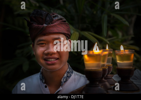 Einen balinesischen Mann in traditioneller Kleidung Kerzen tragen, Ubud, Bali, Indonesien Stockfoto