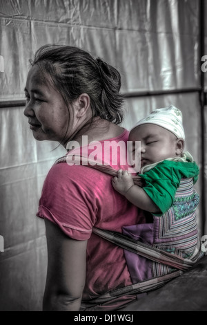 Thailändische Mutter, die Kleinkind in einer Rückenschlinge trägt. Thailand S. E. Asien Stockfoto