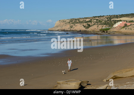 Marokko, Taghazout Dorf in der Nähe von Agadir, Europäische pensionierter Mann zu Fuß seine Hunde am Strand von Tamraght Strand Stockfoto