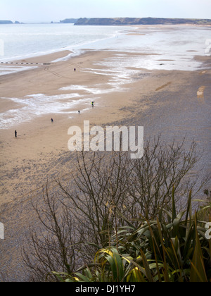 Eine Streuung von Menschen im frühen Frühling Sonnenschein am Strand von South Beach, Tenby, Pembrokeshire, Großbritannien Stockfoto