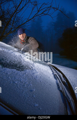 Mann von Frost bedeckt Auto Windschutzscheibe kratzen Eis. Stockfoto