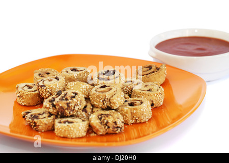 Zwieback mit Sesam, Oliven auf orange Teller und roter Soße isoliert auf weißem Hintergrund. Stockfoto