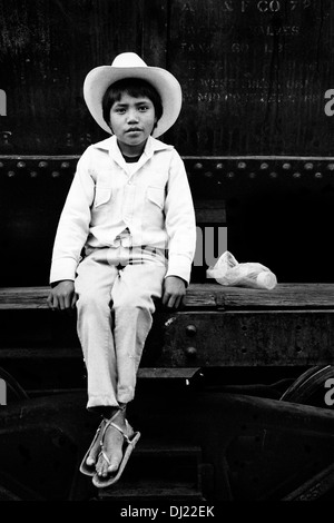 Eine mexikanische junge, weiße Cowboy Kleidung, sitzt auf dem Wagen des legendären Chihuahua-Pacífico Zuges im nördlichen Mexiko. Stockfoto