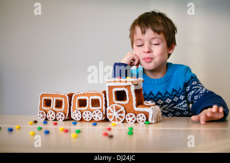 Fröhlicher Junge mit Weihnachtszug Lebkuchen gemacht Stockfoto