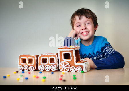 Fröhlicher Junge mit Weihnachtszug Lebkuchen gemacht Stockfoto