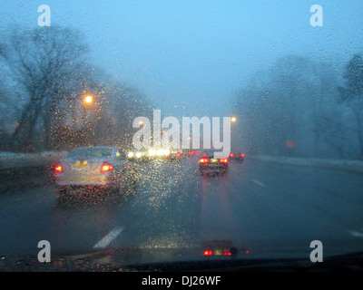 Fahren auf einer Landstraße in der Abenddämmerung im Feierabendverkehr mit Regen und Nebel auf der Windschutzscheibe zu sammeln. Stockfoto