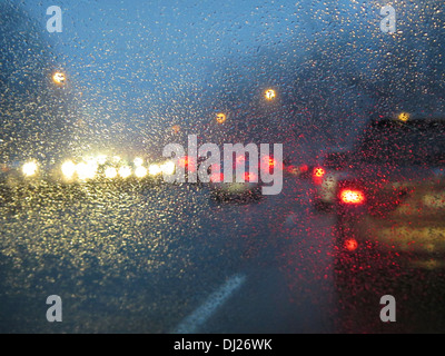 Fahren auf einer Landstraße in der Abenddämmerung im Feierabendverkehr mit Regen und Nebel auf der Windschutzscheibe zu sammeln. Stockfoto