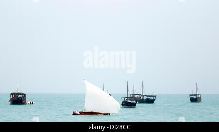 Doha, Katar, 19. November 2013: Eine kleinen Dhau fährt vorbei an andere vertäut am 3. traditionellen Dhow-Festival, am Strand von Katara in der Abenddämmerung. Die Veranstaltung vom November 19-23, findet unter der Schirmherrschaft des Emirs, seine Hoheit Scheich Tamim bin Hamad al-Thani statt. Bildnachweis: Kunst, Reisen/Alamy Live-Nachrichten Stockfoto