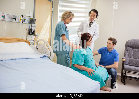 Ärzteteam und Man Looking At schwangere Frau im Krankenhaus Stockfoto
