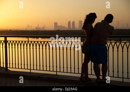 Ein paar fotografieren die Sonnenuntergang Skyline von Abu Dhabi über den östlichen Mangroven Stockfoto