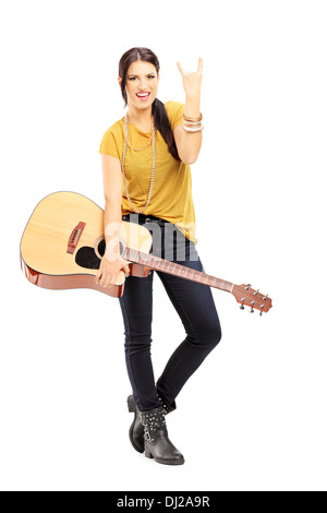 Voller Länge Porträt einer jungen Frau hält eine akustische Gitarre und er ein Rock'n'Roll-Zeichen Stockfoto