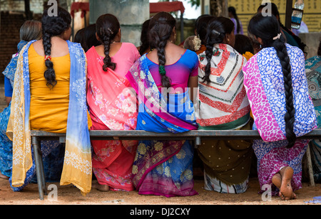 Linie von indischen Frauen tragen bunte Sari saß auf einer Bank. Andhra Pradesh, Indien Stockfoto