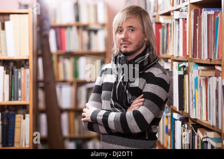 Gut aussehender Mann, Blick in die Kamera in Bibliothek Stockfoto