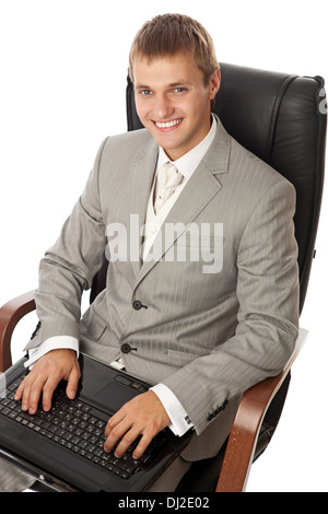 Hübscher junger Mann mit einem Laptop in einem Sessel sitzend Stockfoto