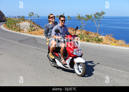 Glückliches junges Paar fahren Roller in den Sommerferien Stockfoto