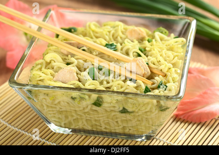 Asiatische Nudelsuppe mit Huhn und Frühlingszwiebeln in Glasschale (selektiven Fokus, Fokus auf das Fleisch zwischen den Stäbchen) Stockfoto