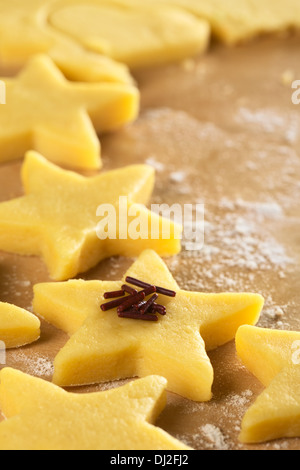 Ungebrannten sternförmige Cookies mit Schokostreuseln auf bemehlten Holzoberfläche (Tiefenschärfe) Stockfoto