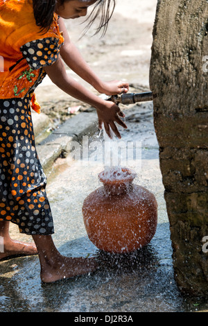 Indische Mädchen tragen einen Plastiktopf mit Wasser aus einem Standrohr in einem indischen Dorf Straße. Andhra Pradesh, Indien Stockfoto