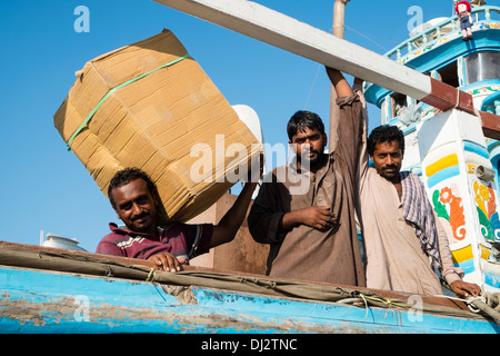 Männer laden Ladung auf Dhaus am Cargo Wharf auf The Creek in Dubai Vereinigte Arabische Emirate Stockfoto