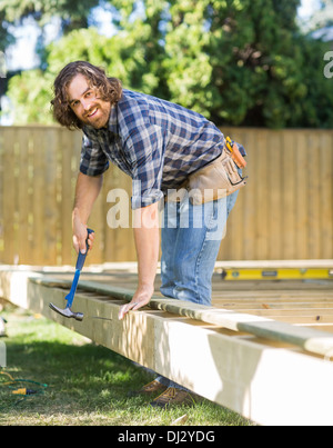 Arbeiter Hämmern Nagel ins Holz am Standort Stockfoto