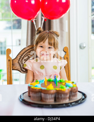 Glückliches Mädchen sitzen vor Kuchen zu Hause Stockfoto