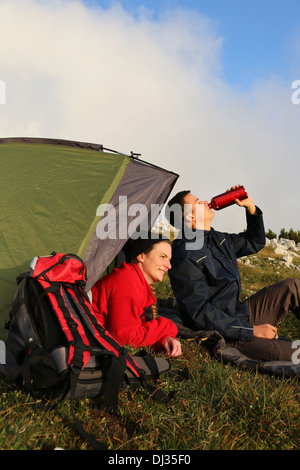 Junges Paar mit einem Zelt ist der Sonnenuntergang in den Bergen Stockfoto