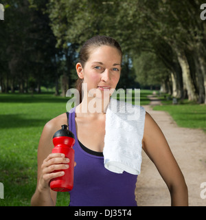 Junge Frau mit einem Getränk nimmt eine Pause beim Sport oder laufen Stockfoto