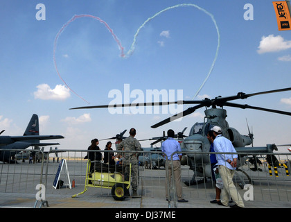 Zuschauer zusehen, wie die Vereinigten Arabischen Emirate Luftwaffe Display Team, Al Fursan, ein Herz in den Himmel über 2013 Dubai Airshow 17 am Flughafen Dubai World Central in Jebel Ali, 18. November 2013 zieht. Die Biennale, das eines der größten aviat Stockfoto