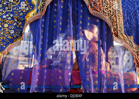 Ausländische Touristen nehmen eine Fahrt in dekorativen Kamel Wagen bei Pushkar Camel fair, Rajasthan Indien. Stockfoto