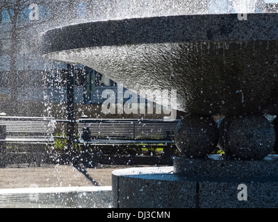 Erfrischendes Wasser Tropfen Spritzwasser aus dem Brunnen im Park. Kalten Beton und warmen Licht durch die Spritzer. Stockfoto