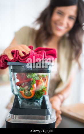 Porträt eines Mädchens mit dem Mixer zu rohen Tomatensauce vorbereiten Stockfoto