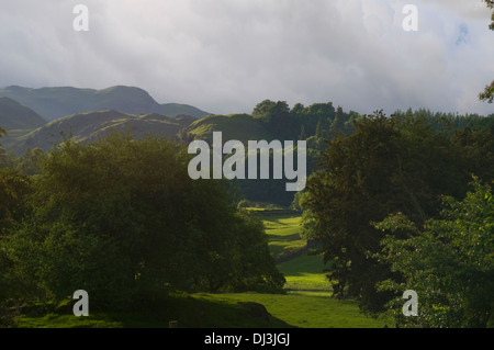 Weiten Blick von der Lake District National Park es ist sonnenbeschienenen Hügeln und Tal Wälder und grüne Weiden Stockfoto