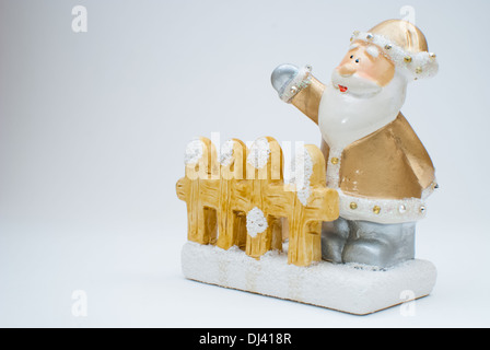 Goldenen alten Zeit Santa Claus Figur stehen hinter Gartenzaun und winkte mit einer Hand geschossen im Studio mit hellem Hintergrund Stockfoto