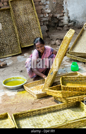 Inderin mit Kurkuma Wasser als Desinfektionsmittel, um Seidenraupe Schalen in einem ländlichen Dorf zu reinigen. Andhra Pradesh, Indien Stockfoto