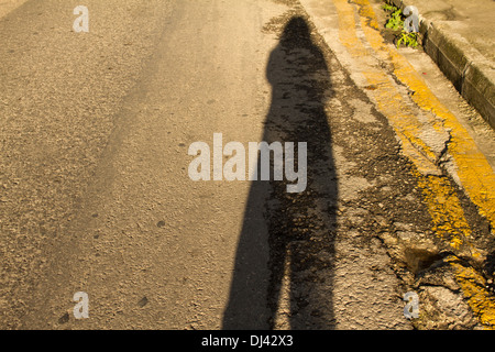 Schatten Sie auf einer schwarzen gebrochen Straßendecke mit einer gelben Linie Stockfoto