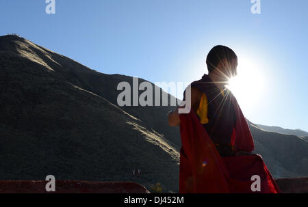 Lhasa, Tibet. 21. November 2013. Junger Mönch Soinam Gyaco genießt die Sonne auf dem Dach des Klosters Gonggar Qoide in Gonggar Grafschaft von Südwesten Chinas Tibet autonome Region, 20. November 2013. Soinam Gyaco, 19, ist der Sohn einer Bauernfamilie in der Nähe des Klosters. Angetrieben von seiner buddhistischen Glaubens, wählte er das Leben eines Mönchs in Gonggar Qoide Kloster nach dem Abitur. Als der jüngste unter den einige 60 Mönchen im Kloster, Soinam haben, mehr Zeit auf Sutras, dem tibetischen Kanon und anderes wissen als seine Mitbrüder. Bildnachweis: Xinhua/Alamy Live-Nachrichten Stockfoto