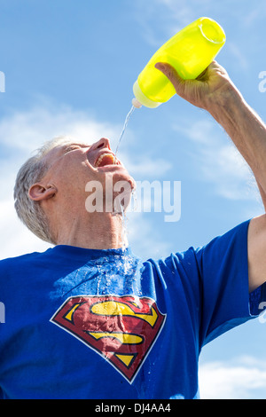 Reifer Mann mit Superman-T-Shirt trinken aus der Flasche Wasser, USA Stockfoto