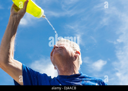 Ein älterer Mann, der Wasser über sein Gesicht schüttet, um die Hitzeerschöpfung zu lindern, USA Stockfoto