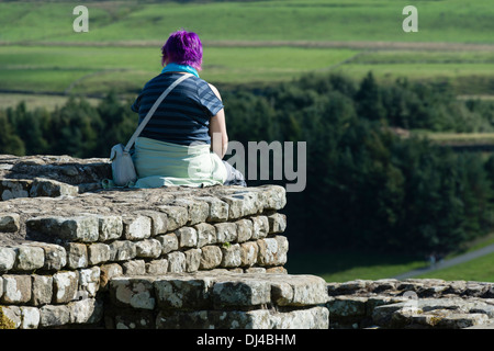 Mädchen sitzen auf der Mauer am römischen Kastells Housesteads Stockfoto