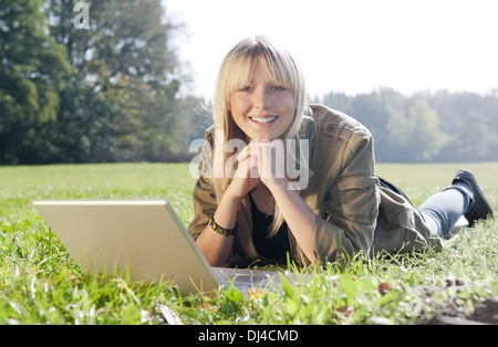 Ypung Frau mit Laptop auf einer Wiese Stockfoto