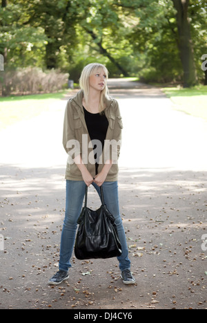 junge Frau steht im park Stockfoto