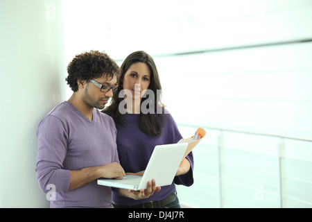 Kollegen, die Blick auf einen Laptop und Papier-Dateien in einem Korridor Stockfoto