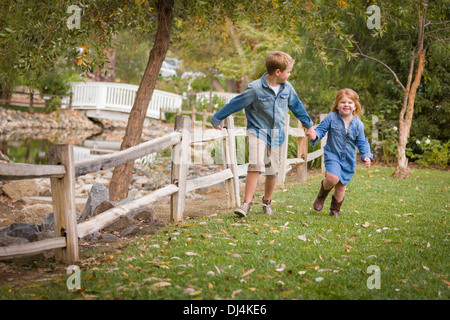 Happy Young Bruder und Schwester zusammen draußen laufen. Stockfoto