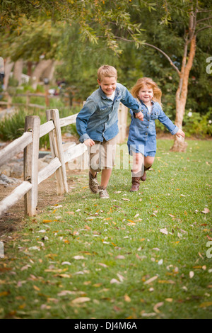 Happy Young Bruder und Schwester zusammen draußen laufen. Stockfoto