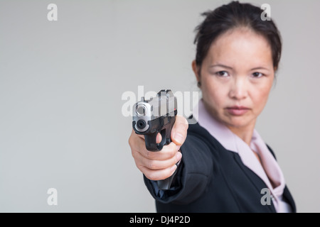 Porträt der Frau in Business-Anzug, mit dem Ziel einer Handfeuerwaffe hautnah Stockfoto