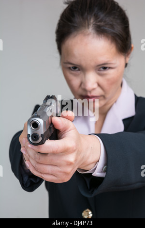 Porträt der Frau in Business-Anzug, mit dem Ziel einer Handfeuerwaffe hautnah Stockfoto