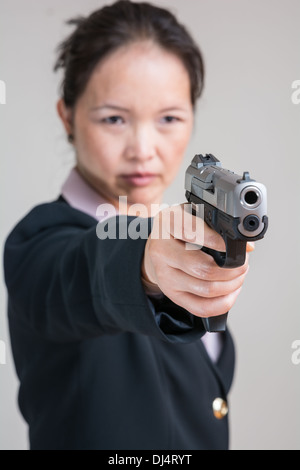 Porträt der Frau in Business-Anzug, mit dem Ziel einer Handfeuerwaffe hautnah Stockfoto